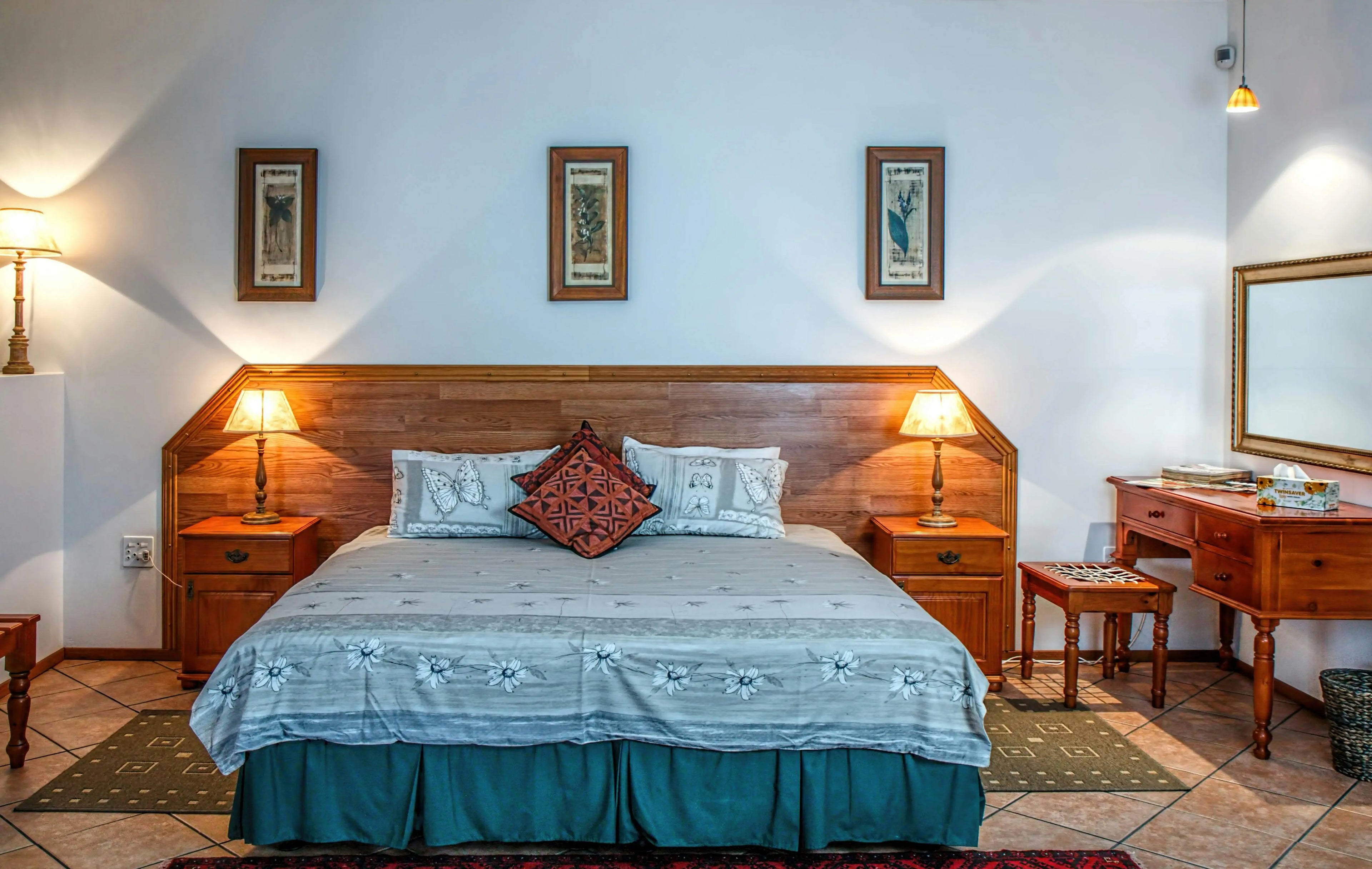 Cozy bedroom featuring a wooden bed, decorative pillows, wooden furniture, and warm lighting, creating a welcoming atmosphere.